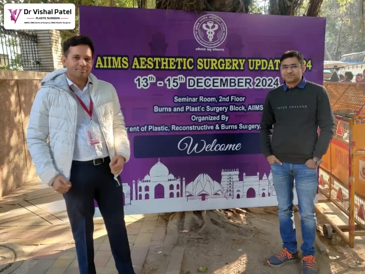 Dr. Vishal Patel standing in front of AIIMS Conference banner.