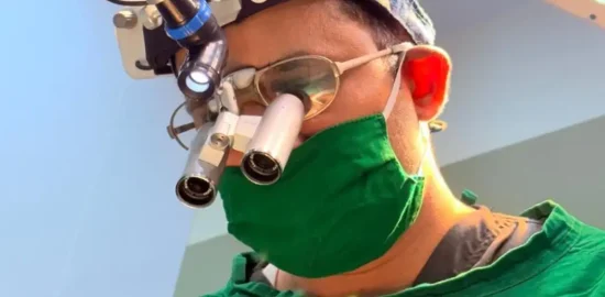 Dr. Vishal Patel wearing surgical binoculars.
